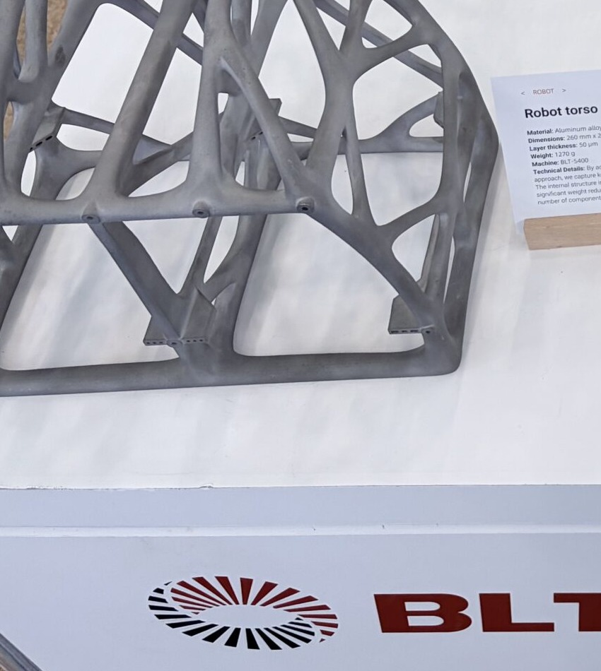 Alternate showroom view of a metal additive robot torso lattice blank with information card
