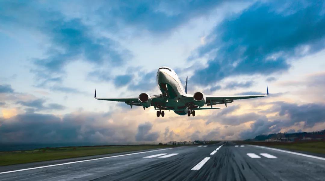 Commercial airliner on approach over a runway under mixed cloud lighting