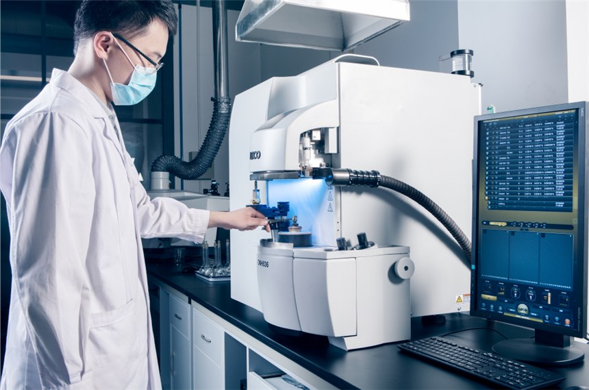 Technician operating a materials analyzer in a lab — context for metal AM coupon discussions